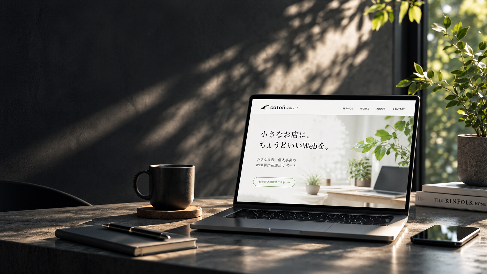 自然光が差し込むデスクに置かれたノートパソコンと、cotoli web std.のWebサイト画面